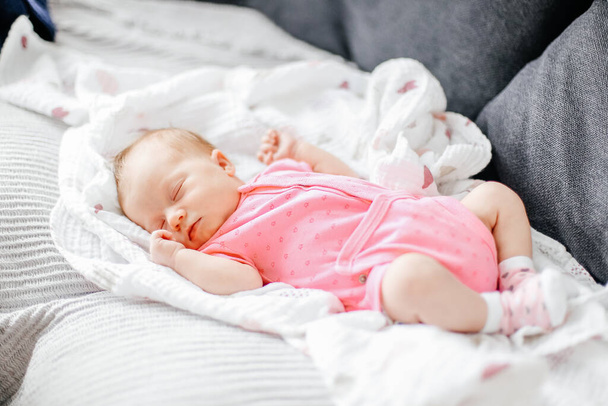 Noworodka dziewczynka spać na białym kocu i noszenie różowych ubrań. - Zdjęcie, obraz