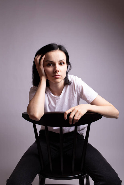 girl in a white t-shirt sits on a chair in the studio - Fotografie, Obrázek