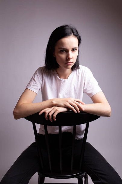 girl in a white t-shirt sits on a chair in the studio - Φωτογραφία, εικόνα