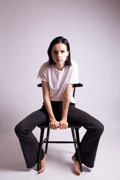 girl in a white t-shirt sits on a chair in the studio - 写真・画像
