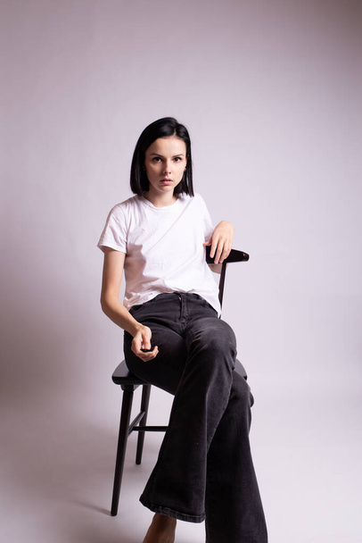girl in a white t-shirt sits on a chair in the studio - Foto, Imagem