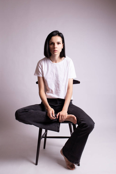 girl in a white t-shirt sits on a chair in the studio - Foto, imagen
