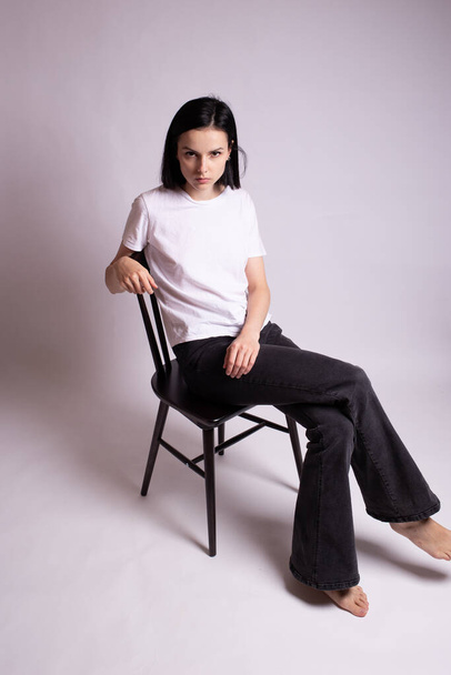 girl in a white t-shirt sits on a chair in the studio - Foto, Imagen
