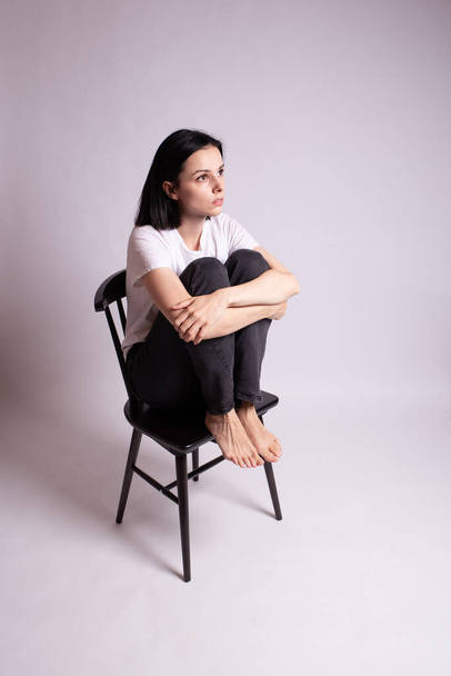 girl in a white t-shirt sits on a chair in the studio - Foto, Imagen