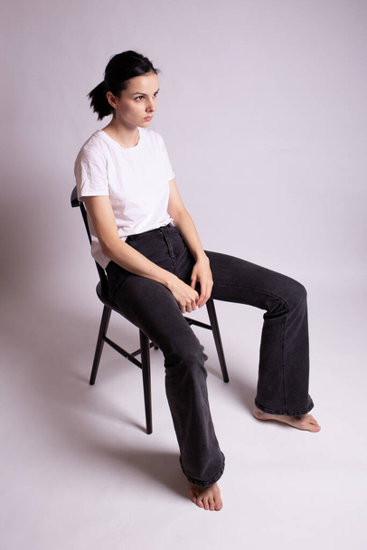 dívka v bílém tričku sedí na židli ve studiu - Fotografie, Obrázek