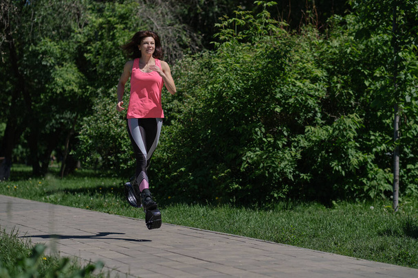Güzel bir kadın parkta koşuyor, bacakları kangoo ayakkabılarıyla. Kangoo Jumping 'i çalıştıran kadınlar - Fotoğraf, Görsel