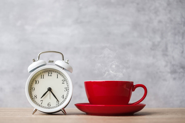 Gorąca kawa espresso i vintage zegar na stole, Red filiżanka kawy w kawiarni lub domu rano. Aktywność, codzienna rutyna, poranek, trening i koncepcja równowagi między życiem zawodowym - Zdjęcie, obraz