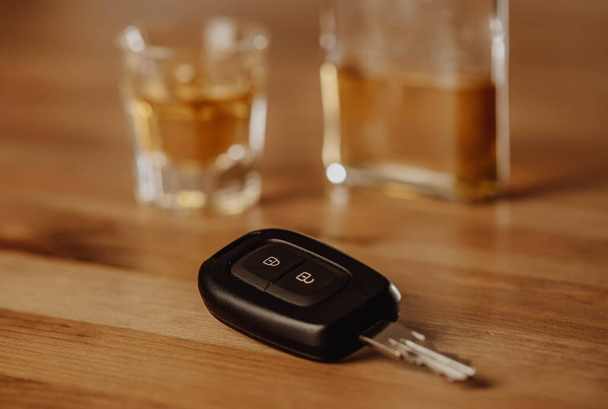Κοντινό πλάνο των κλειδιών του αυτοκινήτου και πολύ ισχυρό αλκοόλ στο τραπέζι, μην πίνετε και οδηγείτε έννοια - Φωτογραφία, εικόνα