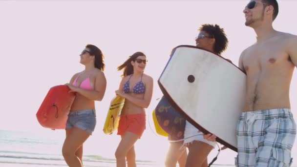 Adolescenti che trasportano assi di corpo attraverso la spiaggia
 - Filmati, video