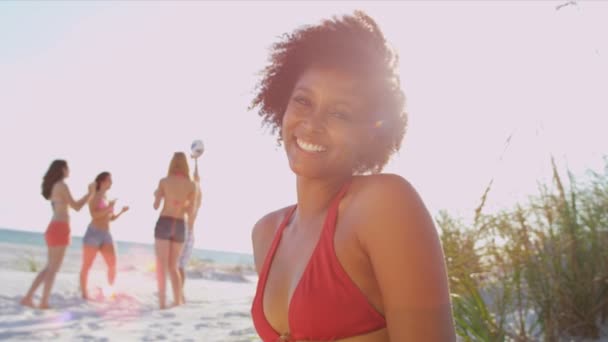Mädchen sitzt am Strand, während Freunde Ball spielen - Filmmaterial, Video