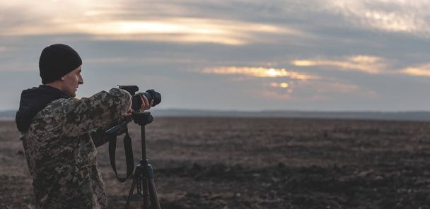 Silhouet van een jonge die graag reizen en fotograaf, nemen foto's van de mooie momenten tijdens de zonsondergang, zonsopgang. - Foto, afbeelding
