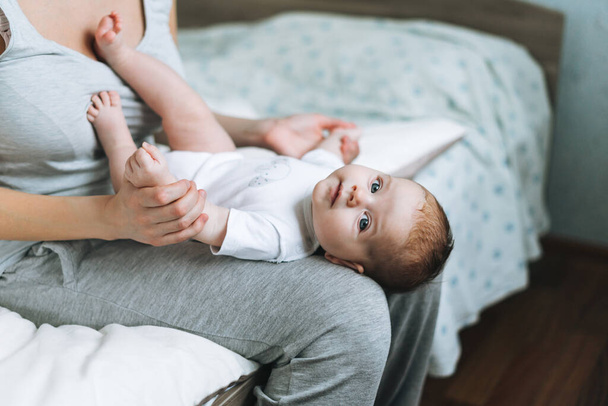 Νεαρή μητέρα διασκεδάζει με το χαριτωμένο κοριτσάκι στα γόνατα κάθεται στο κρεβάτι στο σπίτι, αγάπη συγκίνηση - Φωτογραφία, εικόνα