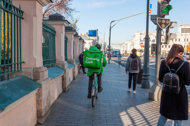 Moscow, Russia - Okt 15. 2021. Delivery club worker rides his bike on a Sretenka Street - Фото, изображение