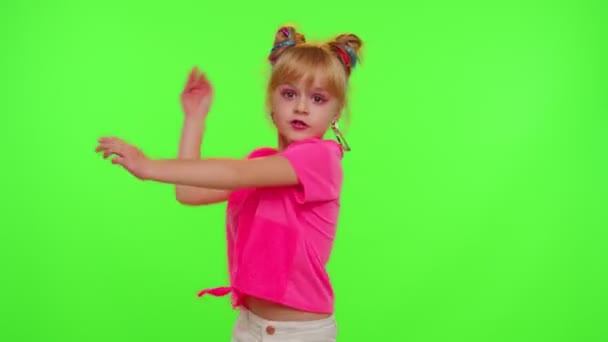 Cheerful funny little teen girl kid dancing at camera filming video using phone on chroma key wall - Video, Çekim