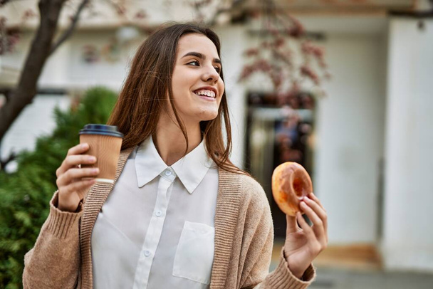 Młoda latynoska bizneswoman uśmiechnięta szczęśliwa jedząc śniadanie w mieście. - Zdjęcie, obraz