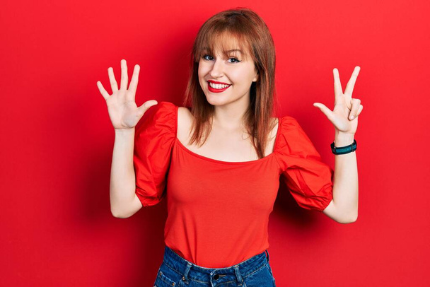 Redhead young woman wearing casual red t shirt showing and pointing up with fingers number eight while smiling confident and happy.  - Photo, Image