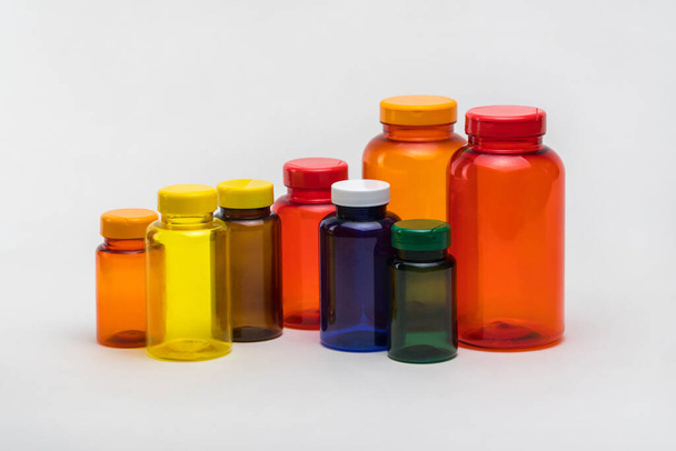 Multi colored transparent plastic pill jars on a white background. Isolated - Zdjęcie, obraz