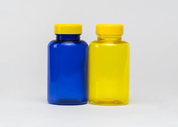 白い背景に複数の色の透明なプラスチック製の丸薬瓶。隔離。 - 写真・画像