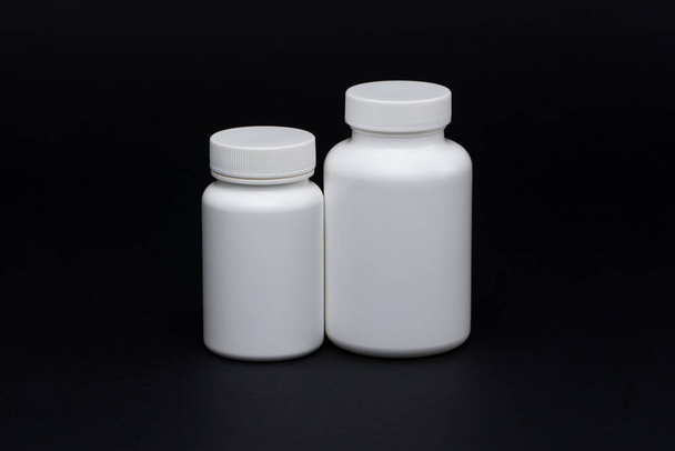 White plastic pill jars on a black background. Isolated - Photo, Image