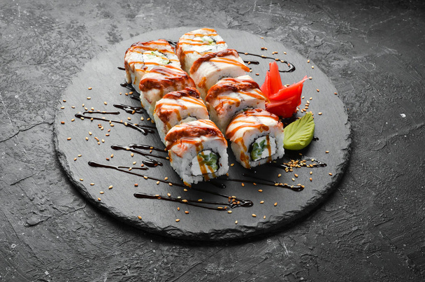 Sushi rolls with eel, cucumber and cheese on a black stone plate. Japanese cuisine. Top view. - Foto, afbeelding