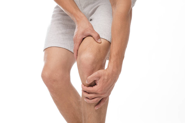 Przycięte tysiącletniego Europejczyka męski sportowiec cierpiący na ból kolana, przyciska rękę do bolesnego miejsca - Zdjęcie, obraz