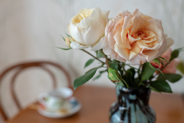 Фотография в тему красивые букеты роз в вазе на деревянном столе. Фото, состоящее из букета натуральных роз в вазе на деревянном столе внутри комнаты. Букет легких роз в вазе на деревянном столе. - Фото, изображение
