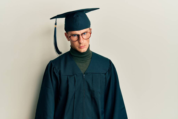 Young caucasian man wearing graduation cap and ceremony robe skeptic and nervous, frowning upset because of problem. negative person.  - Fotó, kép