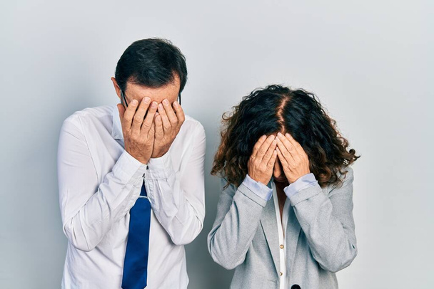 Középkorú pár spanyol nő és férfi, akik üzleti irodai egyenruhát viselnek szomorú arckifejezéssel, miközben sírva fakadnak. depresszió fogalma.  - Fotó, kép