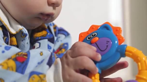 A small child plays with rattles and educational toys. The baby is lying on the floor alone and playing .The baby is developing - Footage, Video