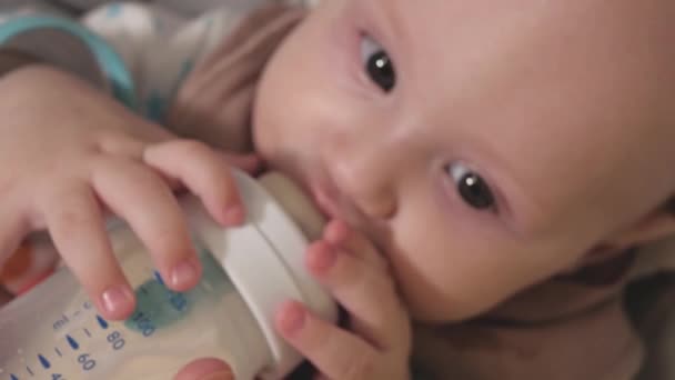 Un bambino mangia latte artificiale da un biberon. Nutrire un bambino close-up.baby.Baby testa primo piano - Filmati, video