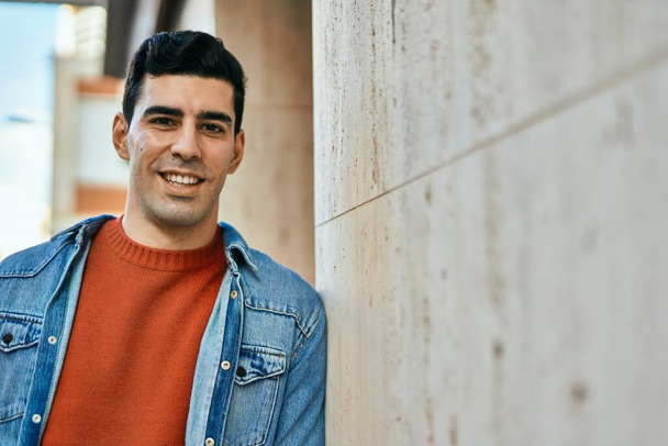 Jeune homme hispanique souriant heureux debout à la ville. - Photo, image