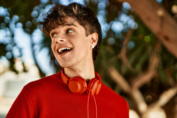 Młody Latynos uśmiecha się szczęśliwy używając słuchawek w mieście - Zdjęcie, obraz