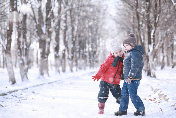 Dzieci spacerują po parku z pierwszym śniegiem - Zdjęcie, obraz
