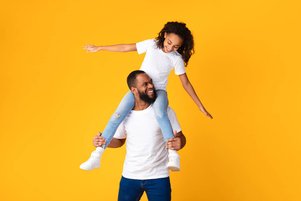 Cheerful African American Man Riding Excited Daughter On His Neck - Foto, Imagen