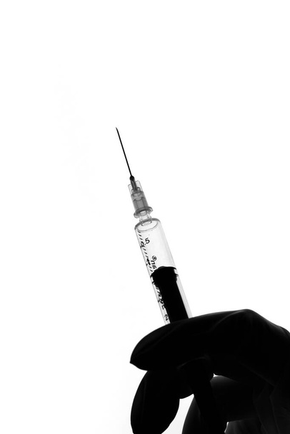 Syringe on doctor's hand wearing white gloves stock image. - Фото, зображення
