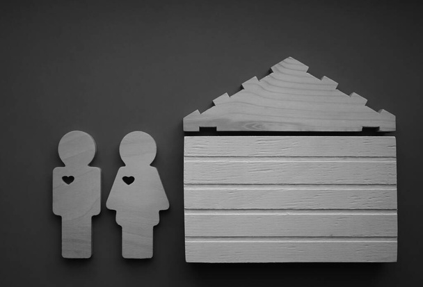couple - man and woman wooden figures and wood house sign on  paper background  - Zdjęcie, obraz