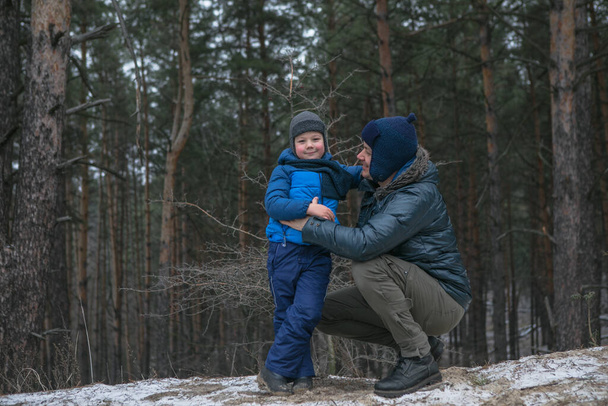 Happy family on a walk outdoors in sunny winter forest, Christmas holidays, father and son play together - Foto, afbeelding