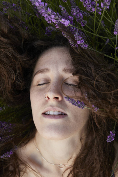 A vertical closeup of a beautiful young woman in the lavender field. - Foto, immagini