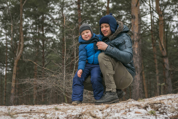 晴れた冬の森の中で屋外で散歩して幸せな家族、クリスマス休暇、父と息子が一緒に遊ぶ - 写真・画像