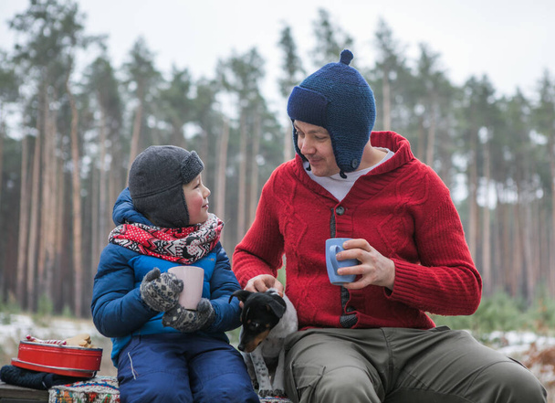 Famiglia felice in una passeggiata all'aperto nella soleggiata foresta invernale, vacanze di Natale, padre e figlio giocano insieme - Foto, immagini