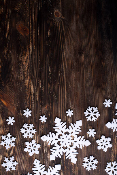 Белые снежинки на темном деревянном фоне, рождественская и зимняя концепция, копировальное пространство. - Фото, изображение