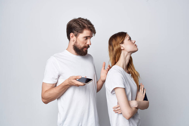 a young couple quarrel jealousy telephones communication light background - Фото, зображення