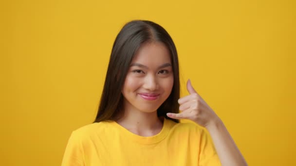 Japán nő Gesturing hívjon kézzel át sárga háttér - Felvétel, videó
