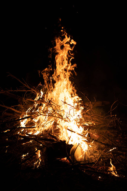 A vertical shot of a big fire flame of a wood burning in the dark, night photography - Foto, immagini