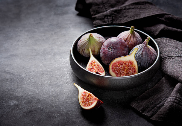 Fresh ripe figs in a black bowl on a dark gray background close up. Concept healthy food. Copy space. - Photo, Image