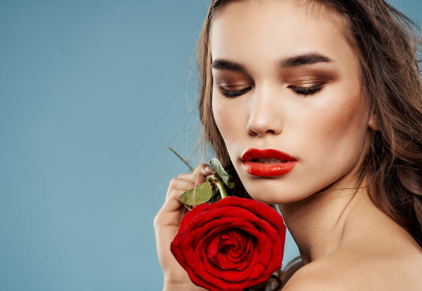 brunette bright makeup rose in hand luxury blue background - Φωτογραφία, εικόνα