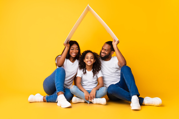 幸せなアフリカ系アメリカ人の両親は娘の上に段ボール屋根を保持 - 写真・画像
