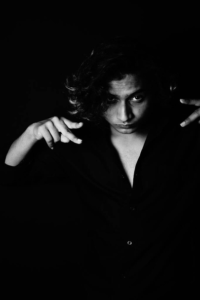 A portrait of a young South Asian male model with long hair on a black background - Valokuva, kuva