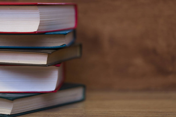 A closeup shot of piled books on a wooden surface - Foto, Bild