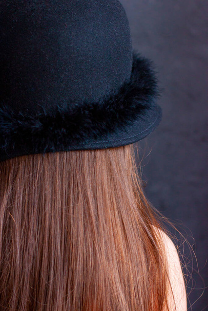 A girl with brown red long hair in a black hat. The view from behind. - Φωτογραφία, εικόνα